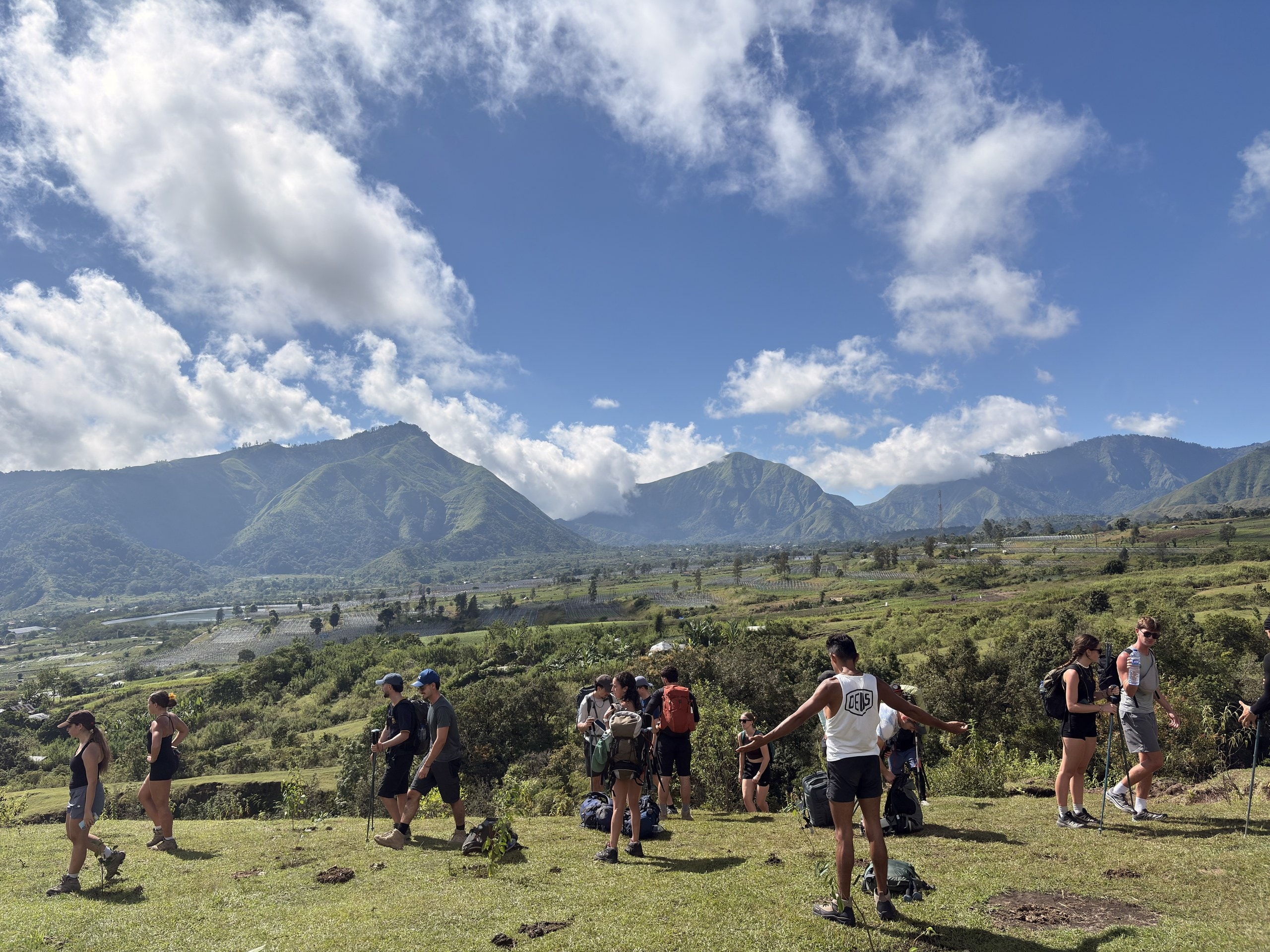 Die Gruppe wandert über eine Hochebene, dahinter Berge und Wolken