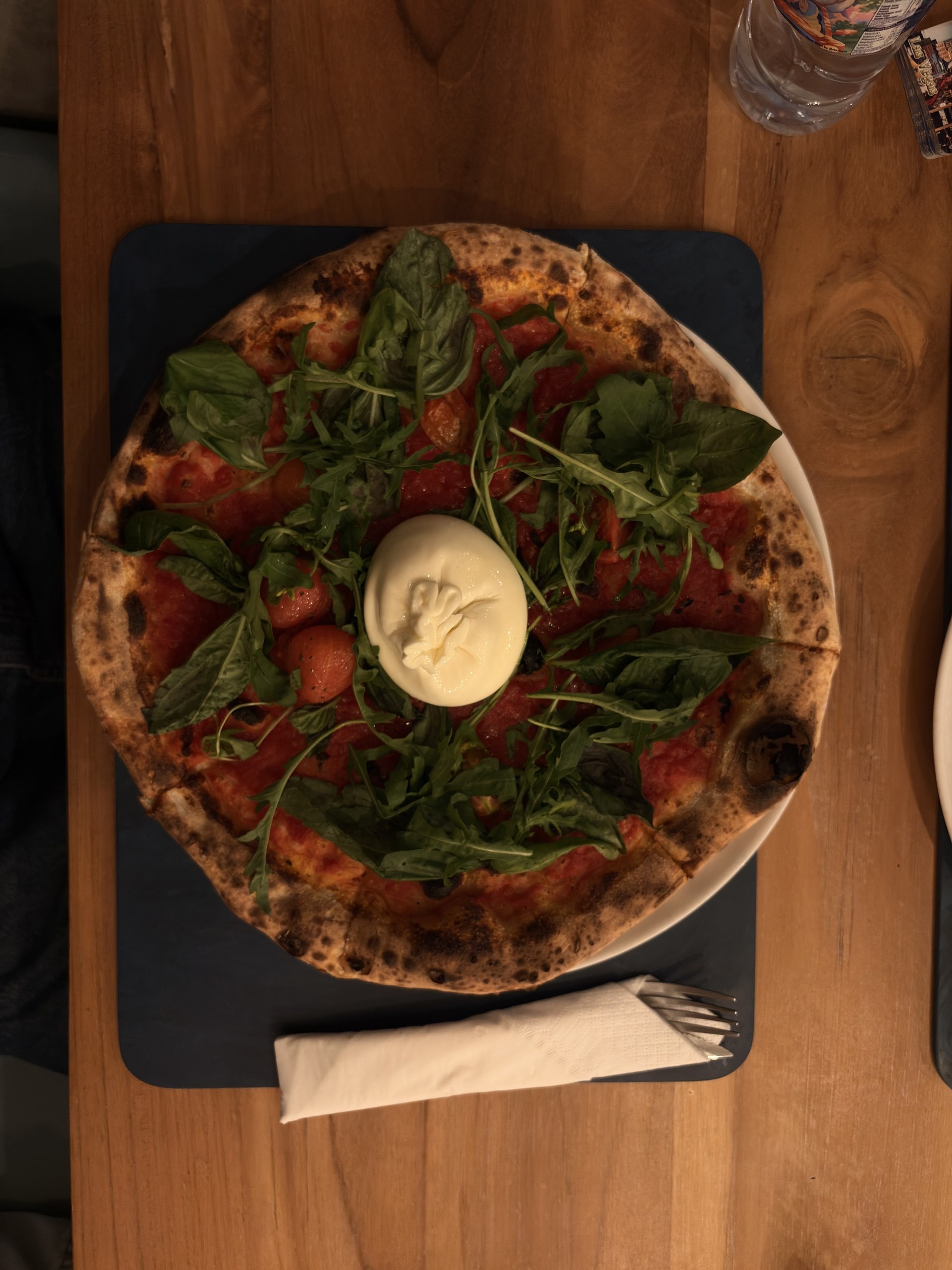 Pizza mit Rucola und Burrata auf einem Holztisch